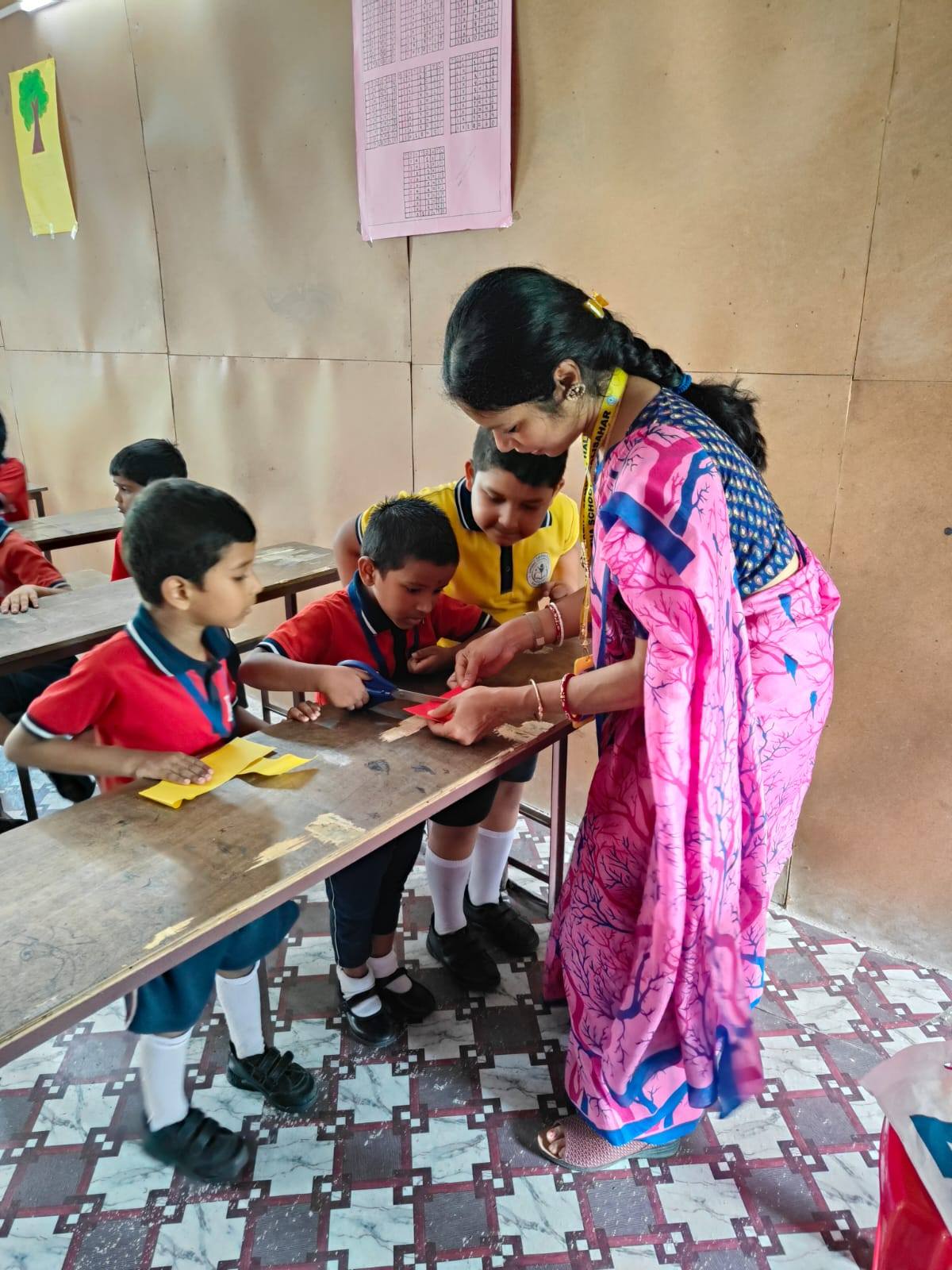 Teacher helping students with a craft activity at Shishu Tirtha School