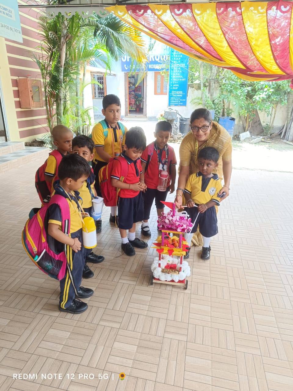 Children with their teacher at the school entrance