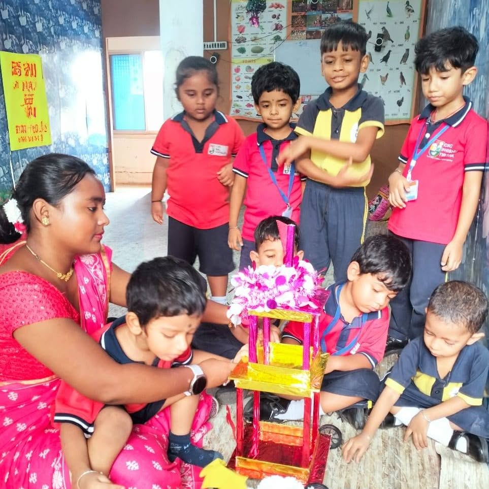 Teacher and children with a craft display in the school corridor